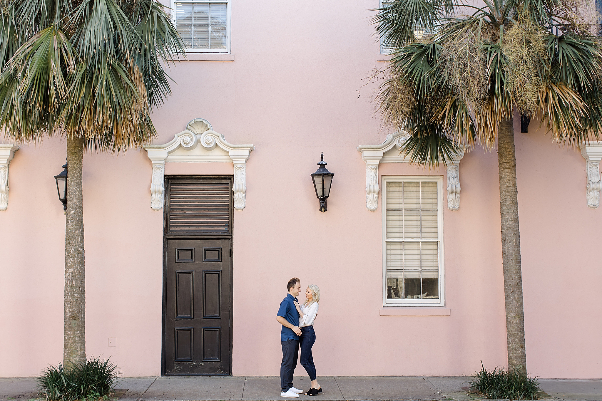 couple hugs outside pink home in Charleston SC