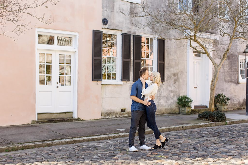 couple kisses on cobblestone road in Charleston during anniversary photos