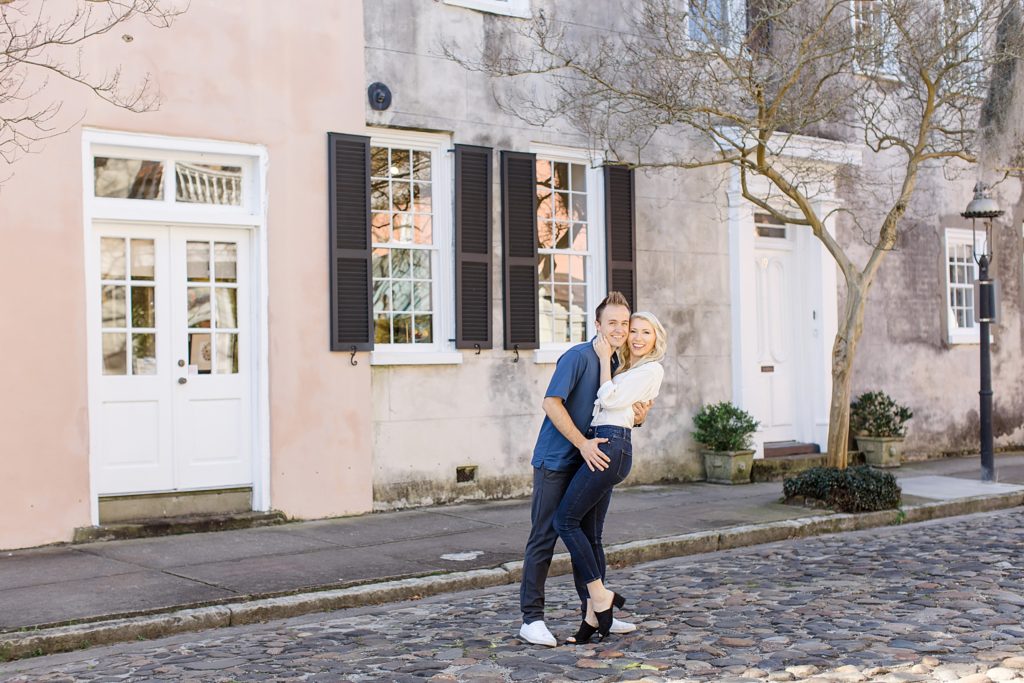 married couple stand on cobblestone road in Charleston SC