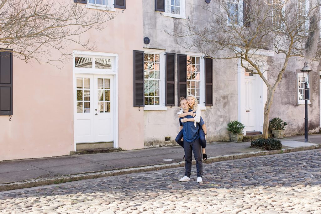 married couple poses on cobblestone road in Charleston