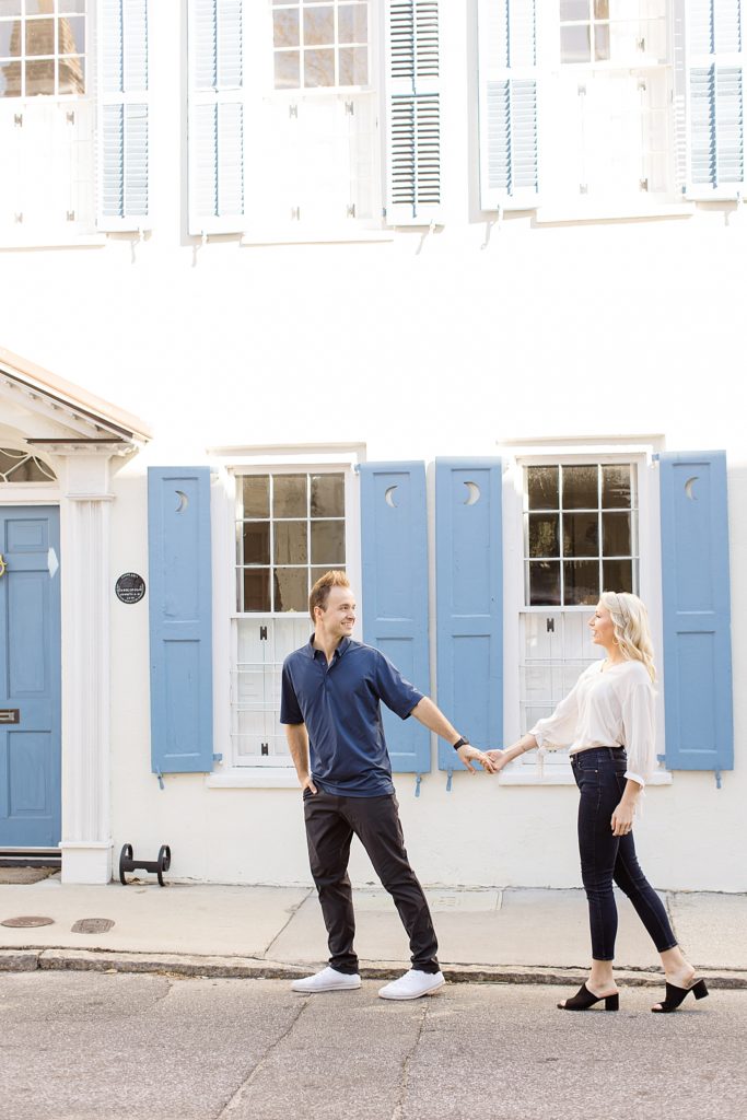 husband and wife walk along white and blue home in Charleston SC