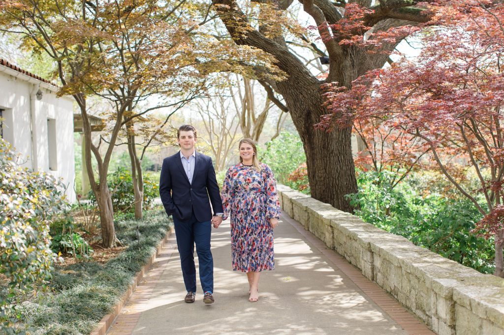 engaged couple walks under trees in Dallas TX