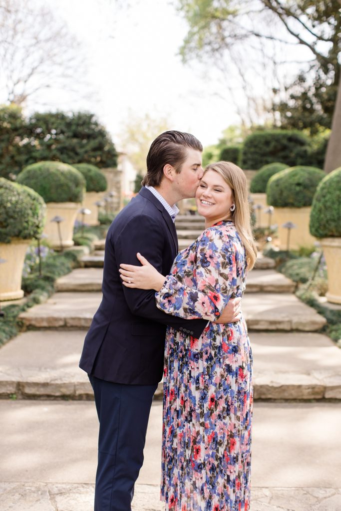 groom kisses bride's forehead by steps at Dallas Arboretum 