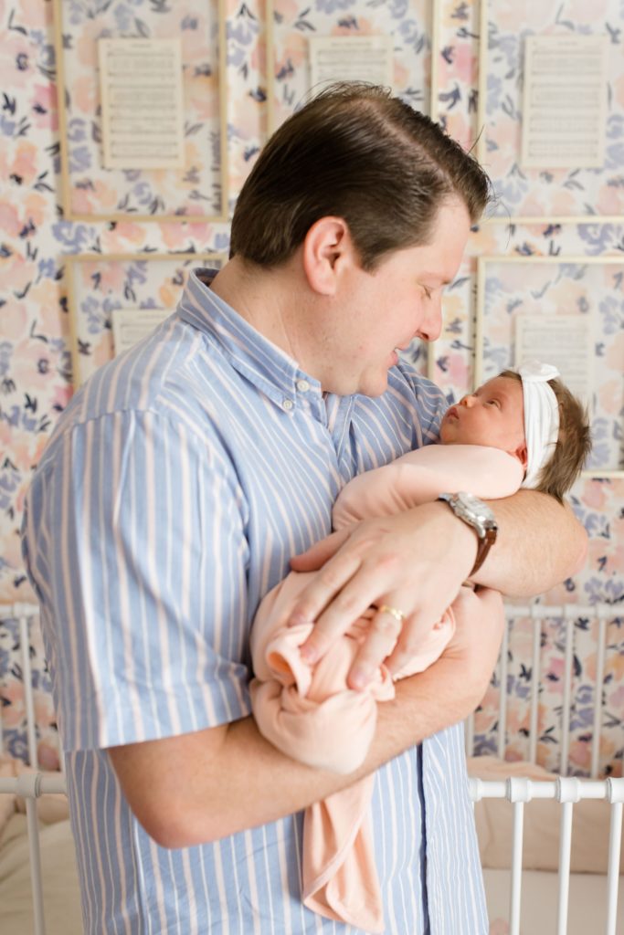dad rocks baby girl during newborn photos at home 