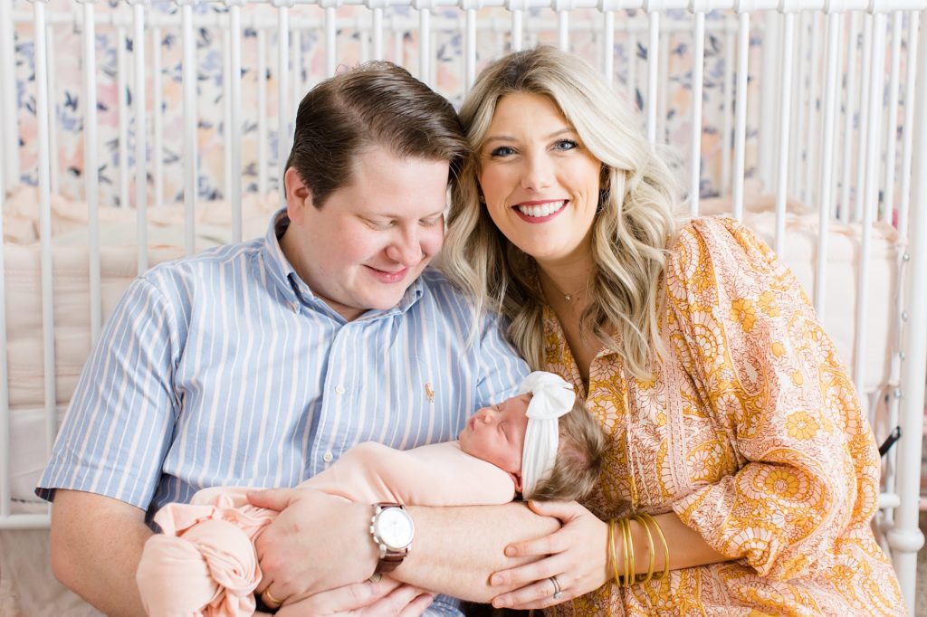new parents hold baby girl by crib during Dallas lifestyle newborn portraits