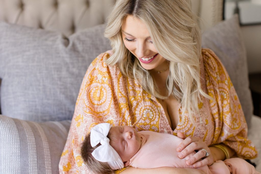 mom sits on bed with baby girl during lifestyle photos at home 