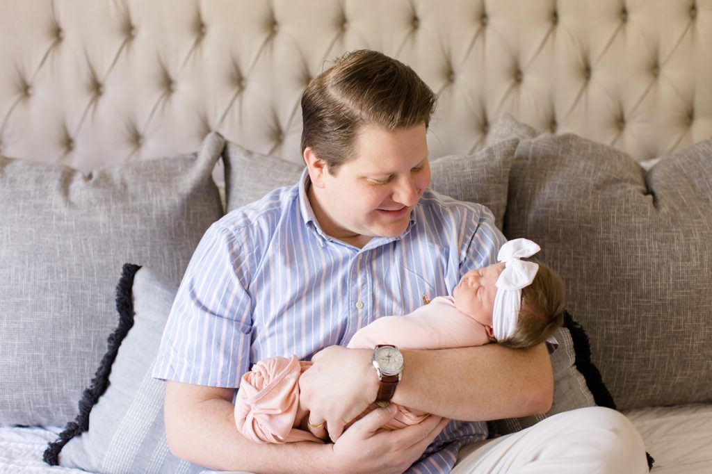 dad holds baby girl during Dallas lifestyle newborn portraits