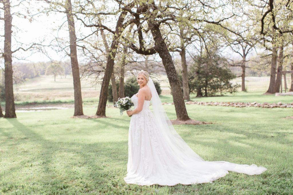 bride looks over shoulder during portraits in field at Oak + Ivy