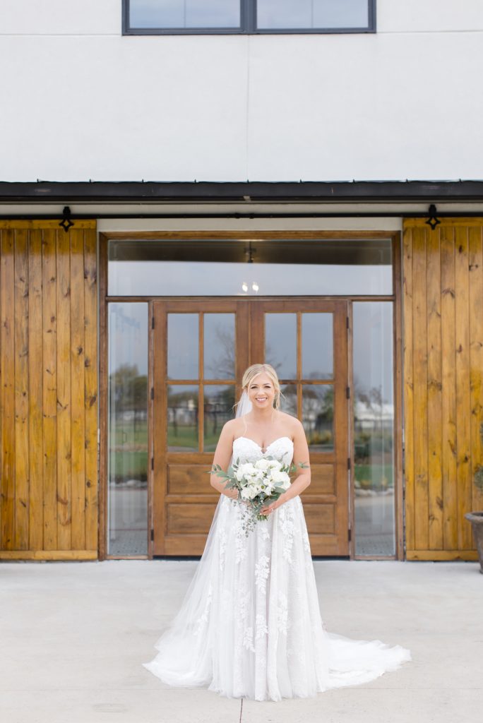 bride poses in front of double wooden doors at Oak + Ivy
