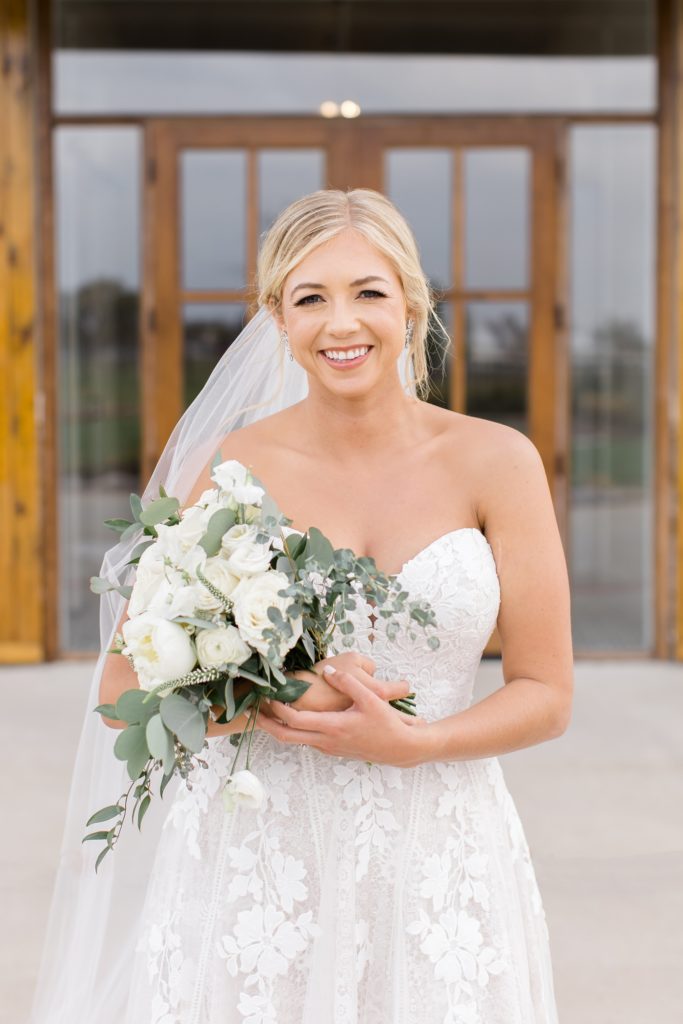 bride holds bouquet in arms with white flowers 