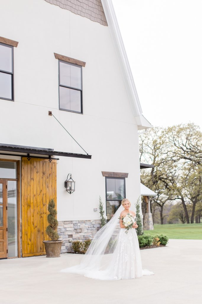bride poses outside wooden door at Oak + Ivy