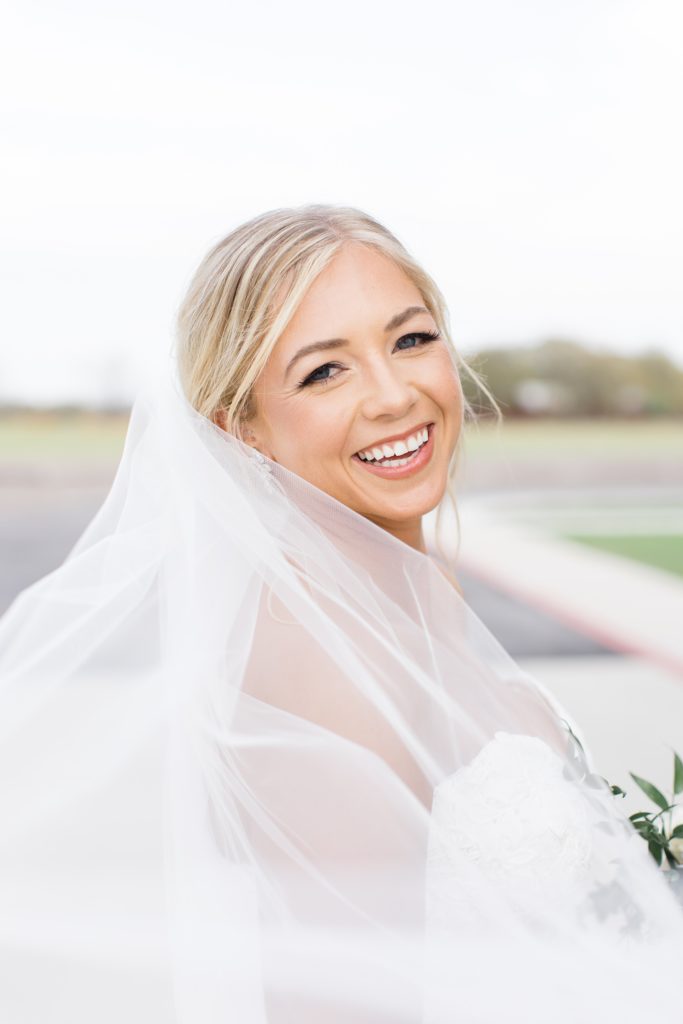 bride laughs with veil wrapped around shoulders during bridal portraits at Oak + Ivy