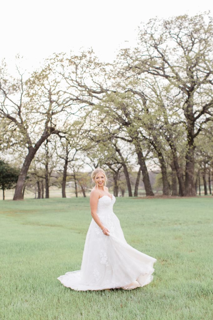 bride twirls her wedding dress in meadow at Oak + Ivy