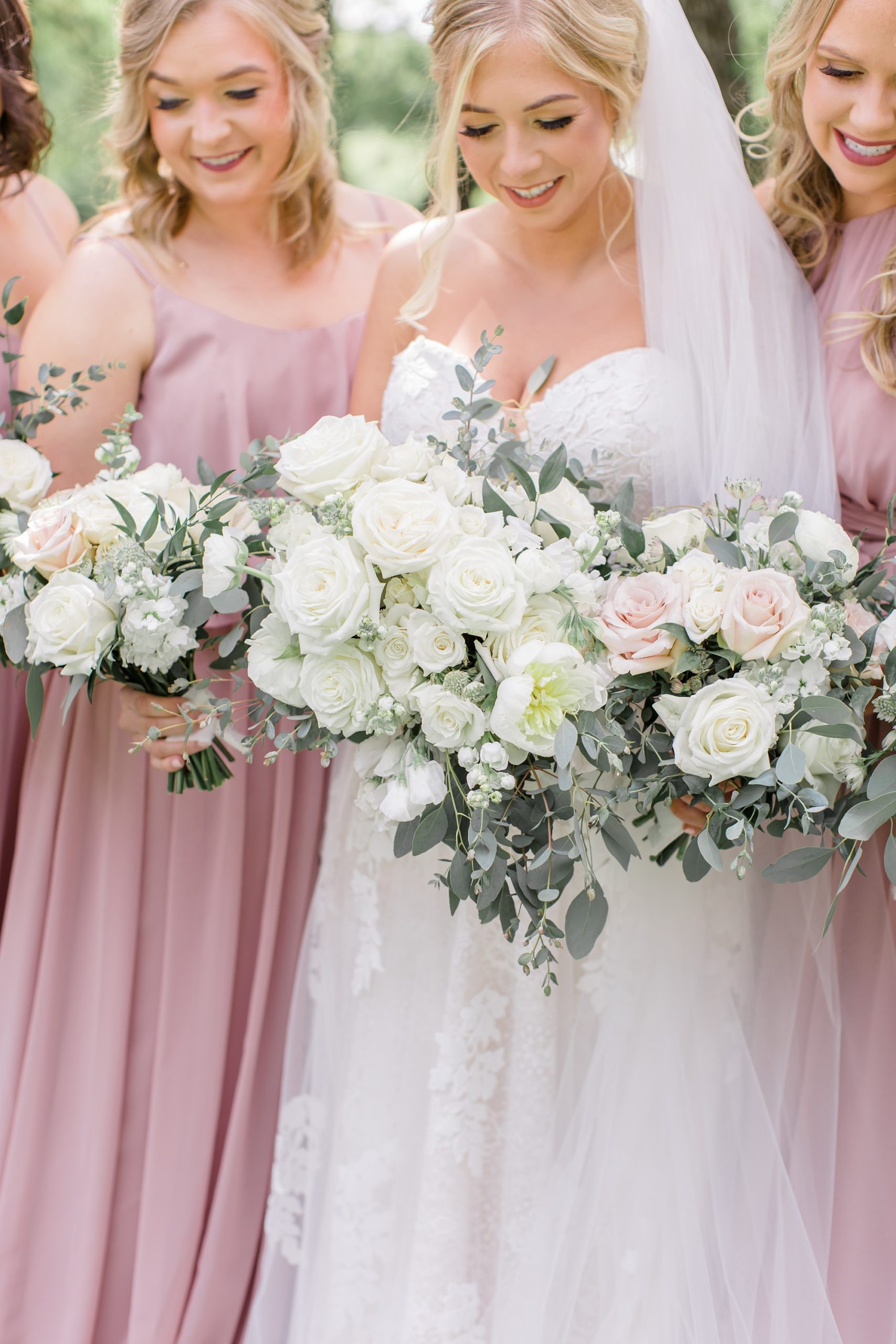 bride holds bouquet of light pink flowers and ivory roses