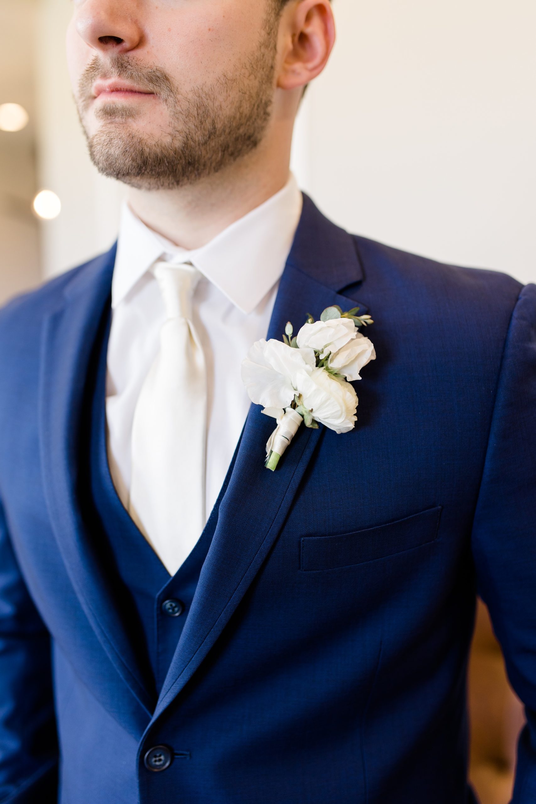 groom in navy suit with white boutonnière for spring wedding at Oak + Ivy