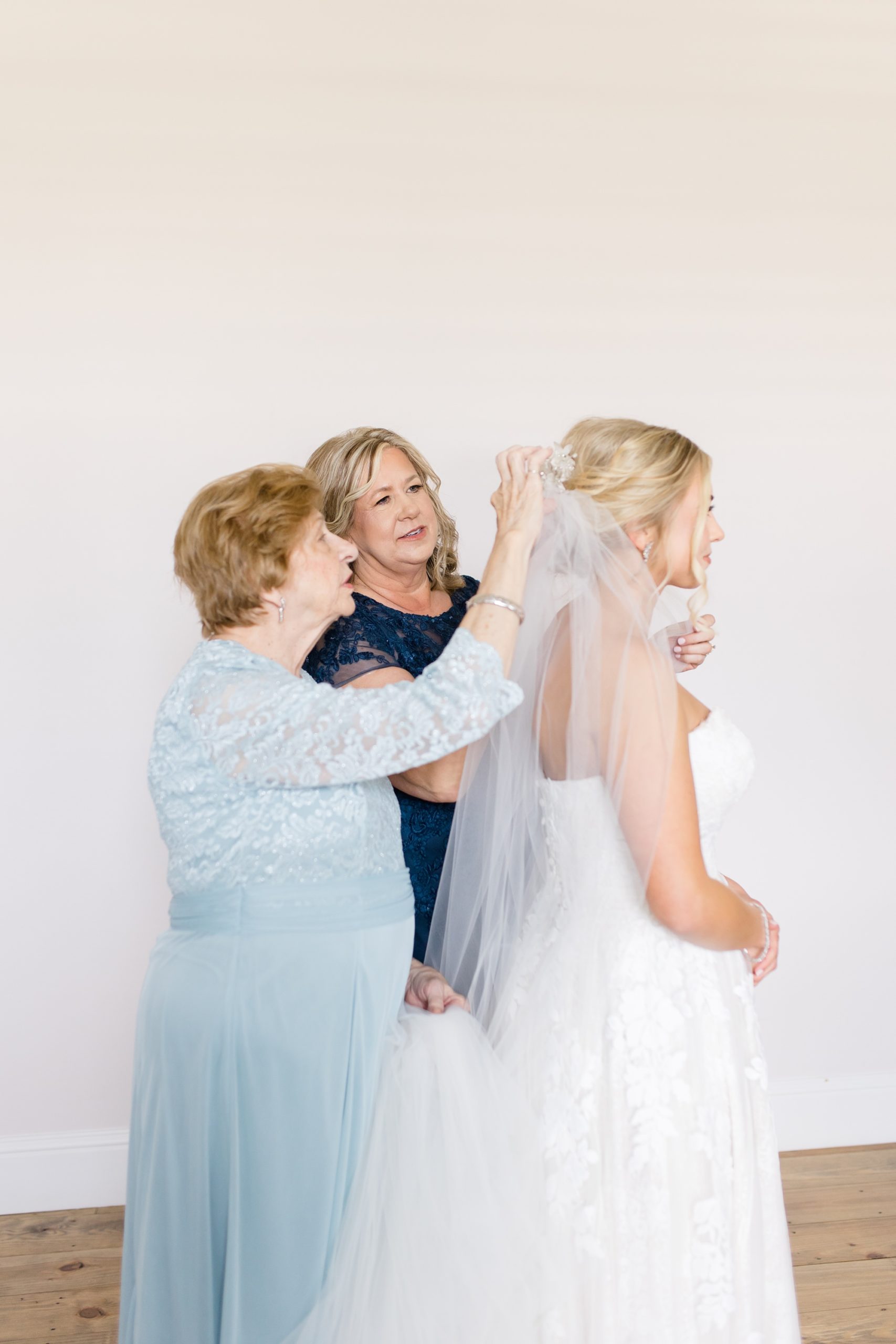mother and grandmother of the bride help bride with veil