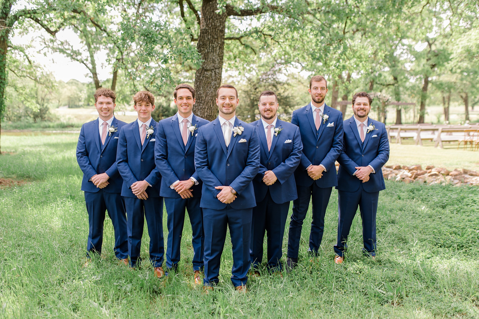 groomsmen in navy suits pose with groom