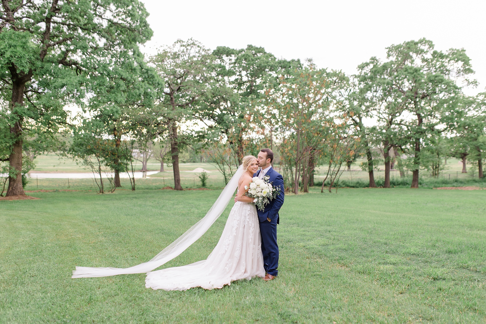 bride and groom pose in field in Texas