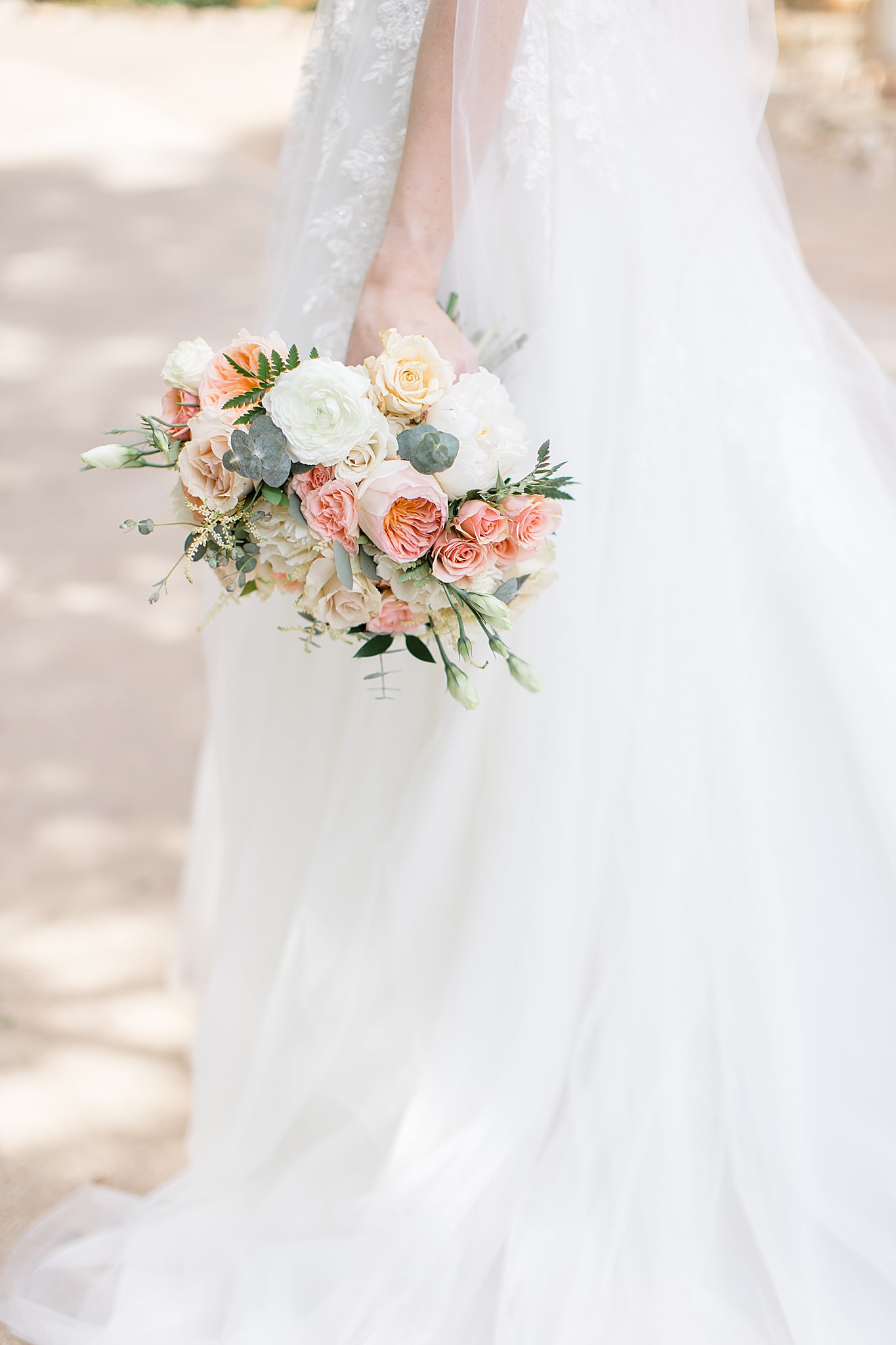 bride holds bouquet of pink and white flowers by side