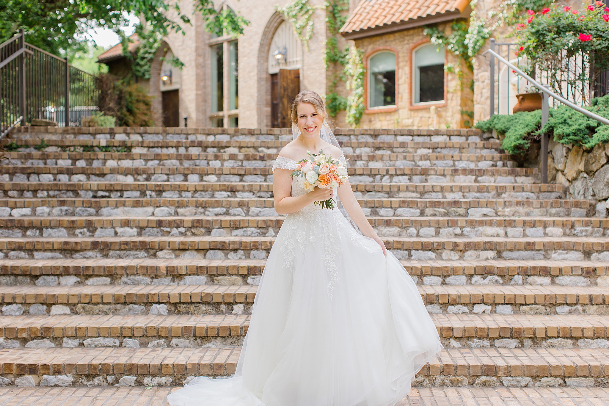 bride holds dress walking down steps at Aristide Mansfield
