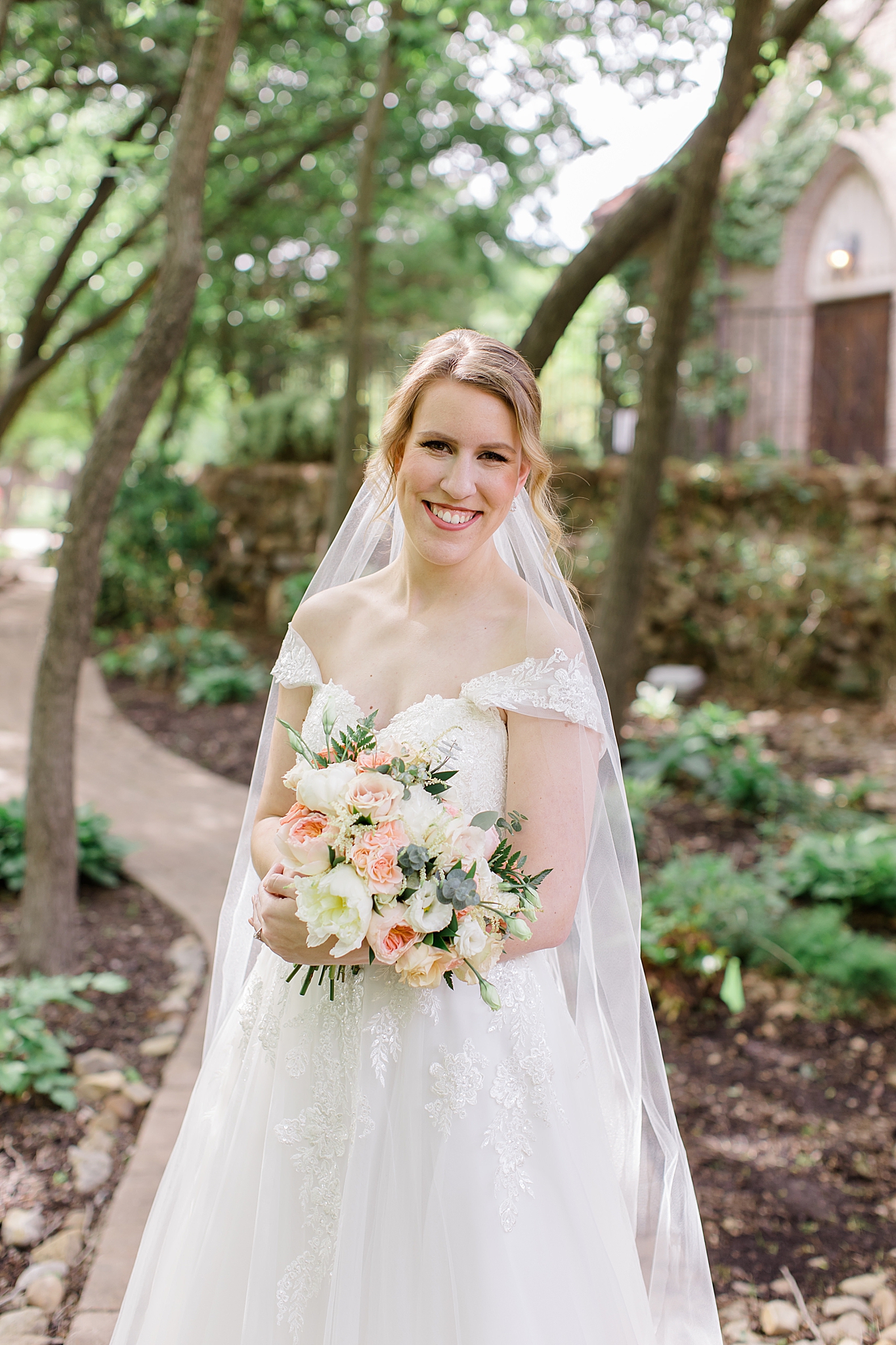 bride holds bouquet of ivory and pink flowers