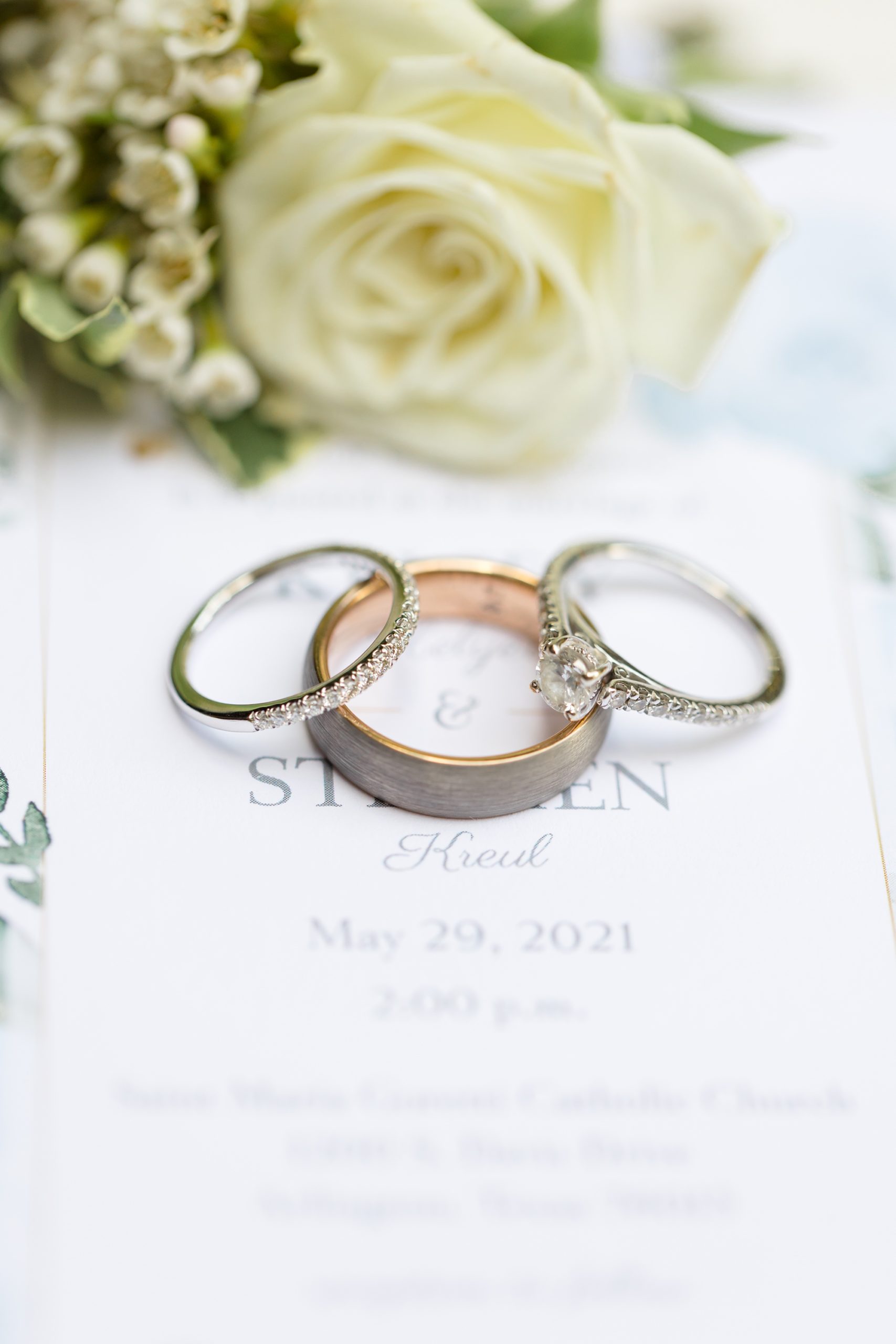 wedding rings rest on invitation suite for Aristide Mansfield wedding