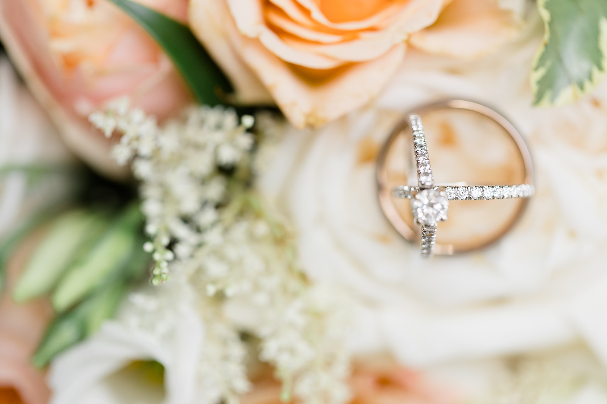 wedding rings sit on peach flower before Texas wedding