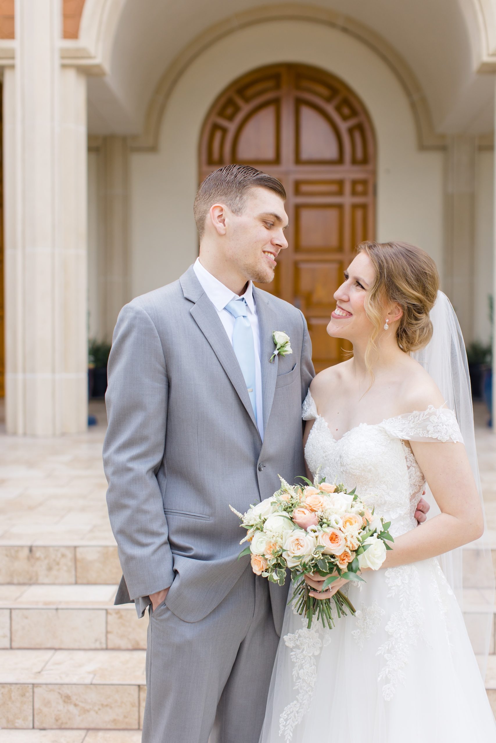 bride and groom smile at each other outside church in Texas