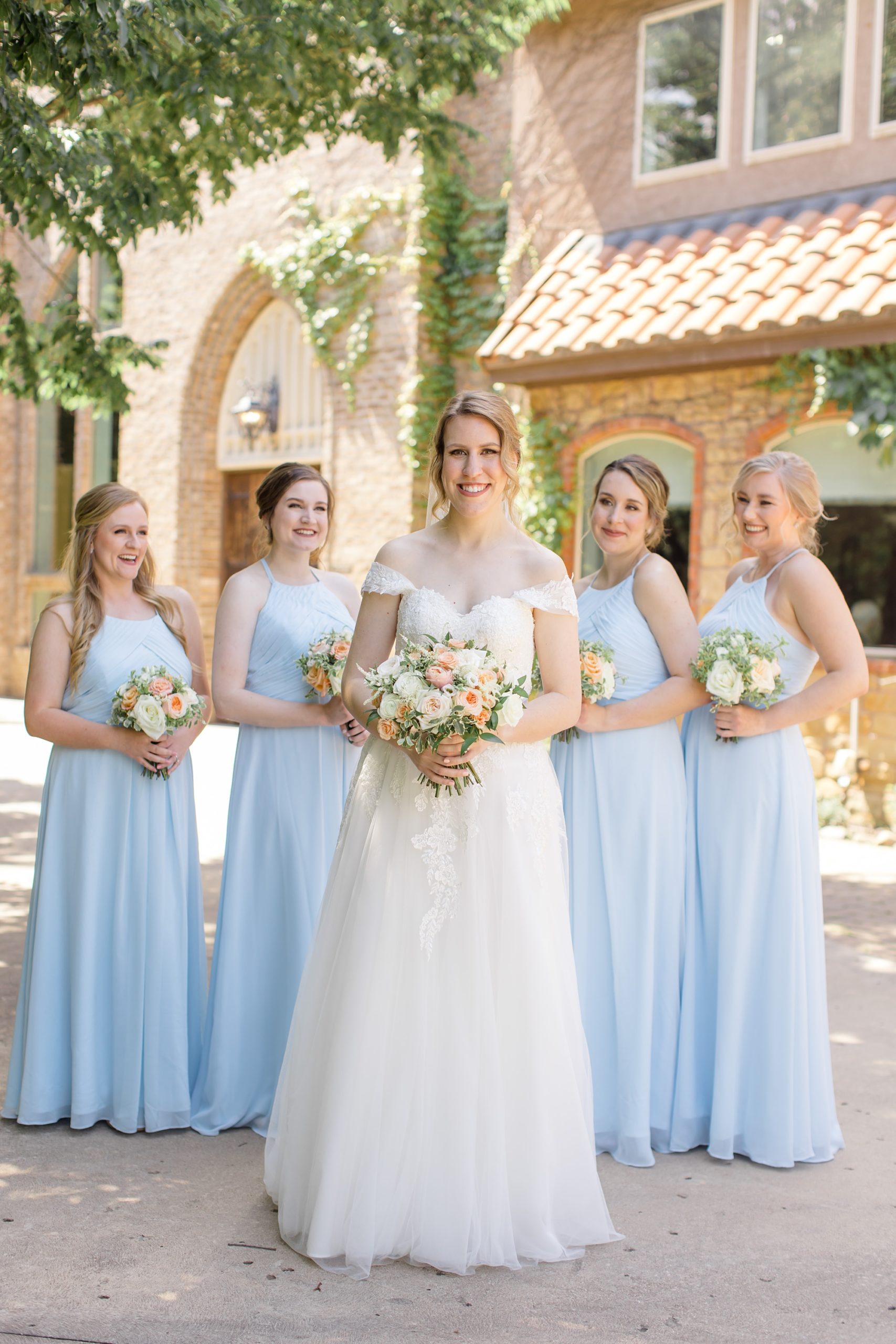 bride stands in front of bridesmaids in pale blue gowns