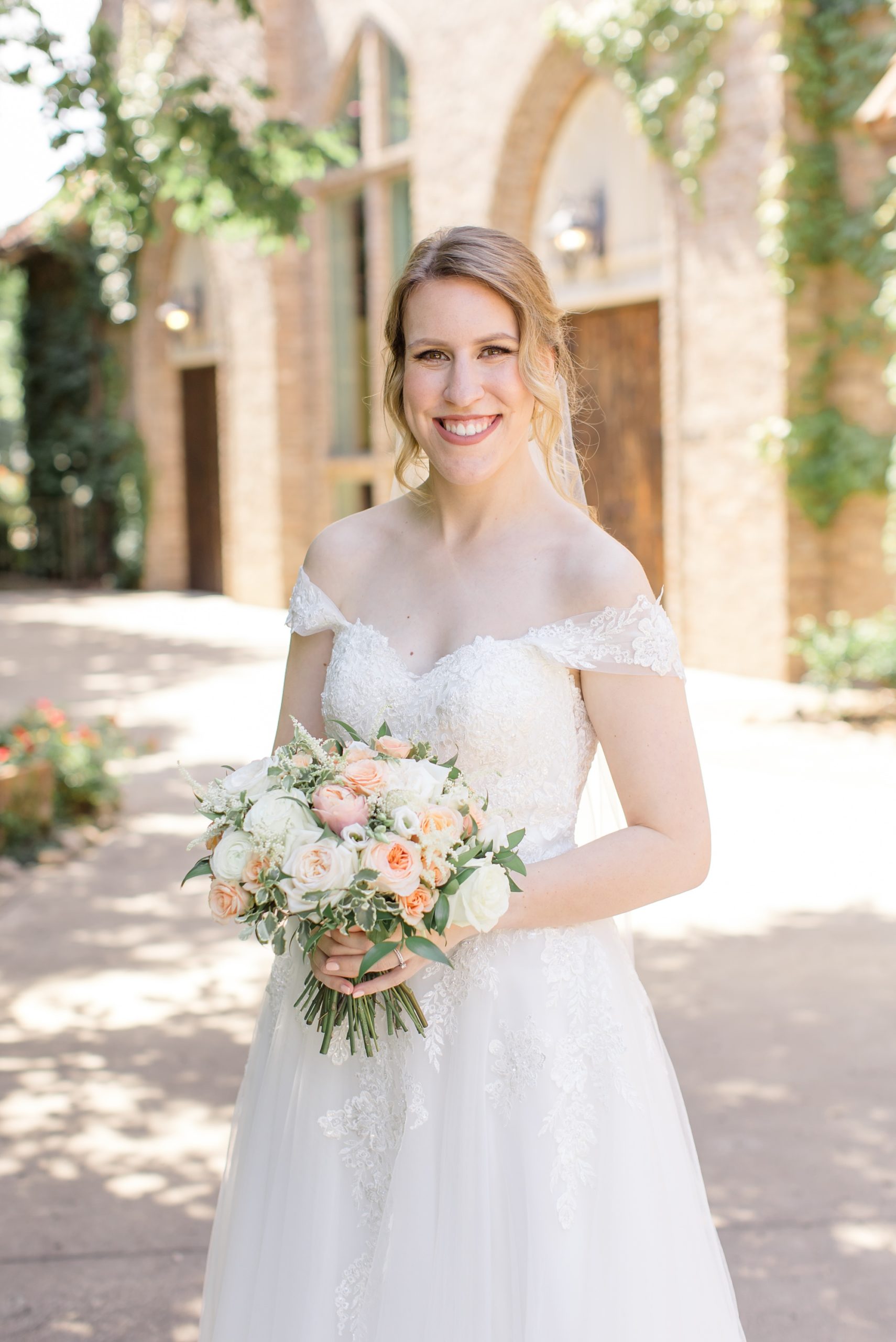 bride smiles holding bouquet outside Aristide Mansfield