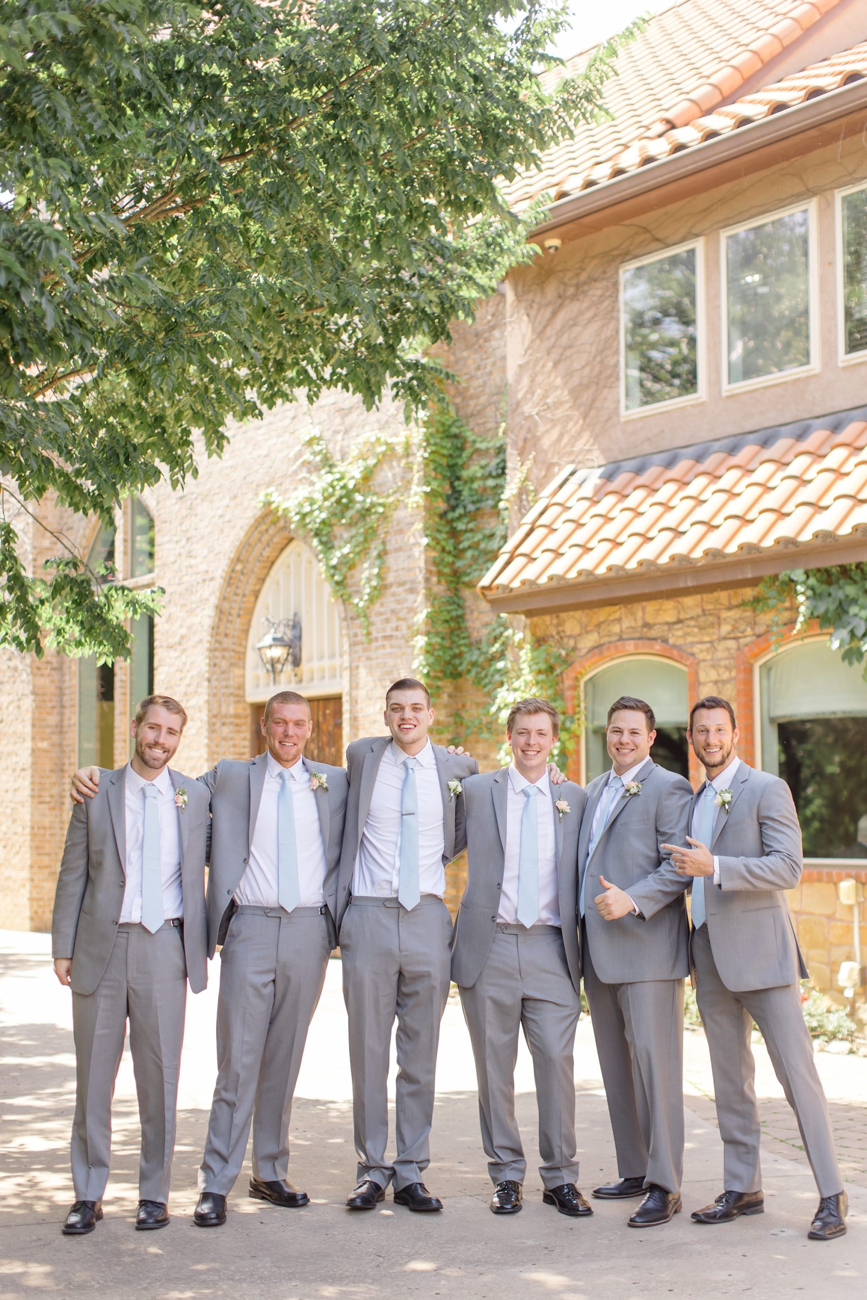 groom and groomsmen pose together outside Aristide Mansfield