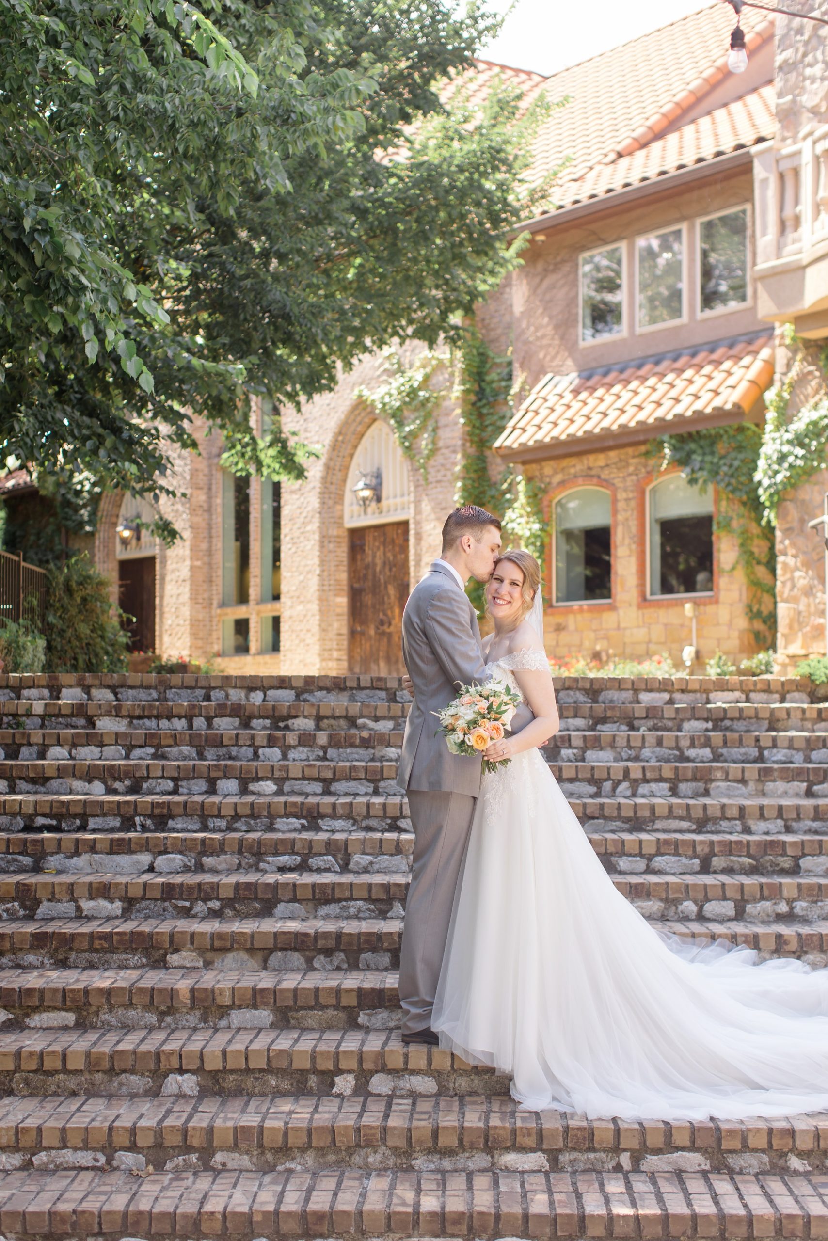 newlyweds stand on stone steps at Aristide Mansfield