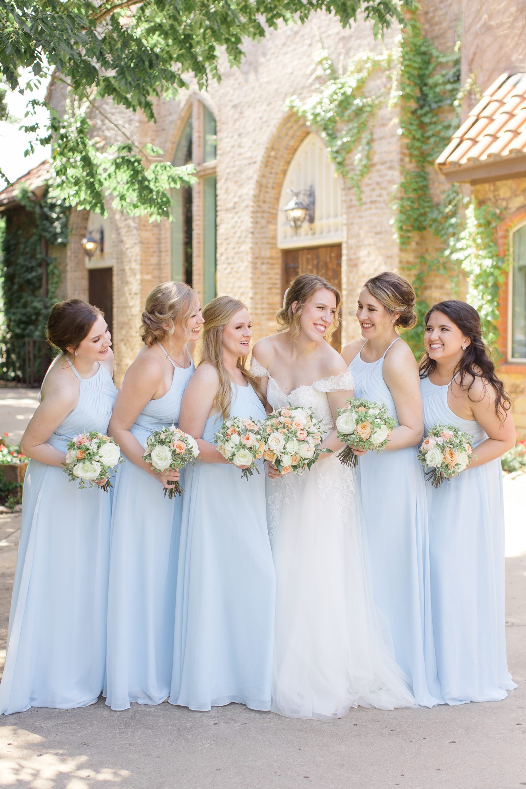 bride smiles with bridesmaids leaning forward 