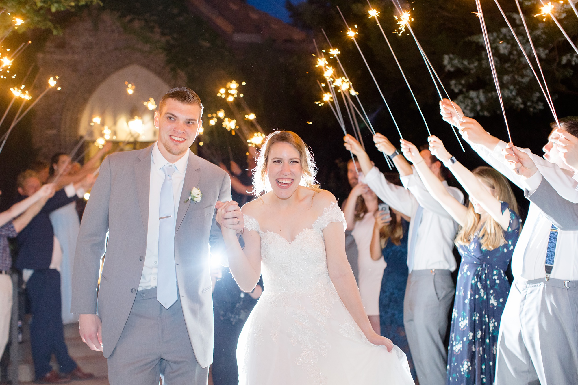bride and groom leave wedding reception with sparkler exit