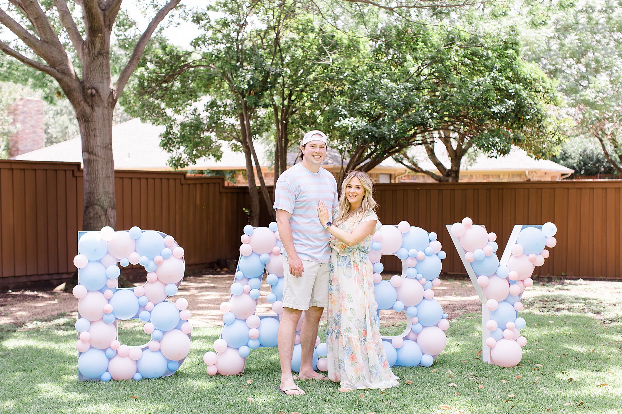 husband and wife pose in front of BABY sign