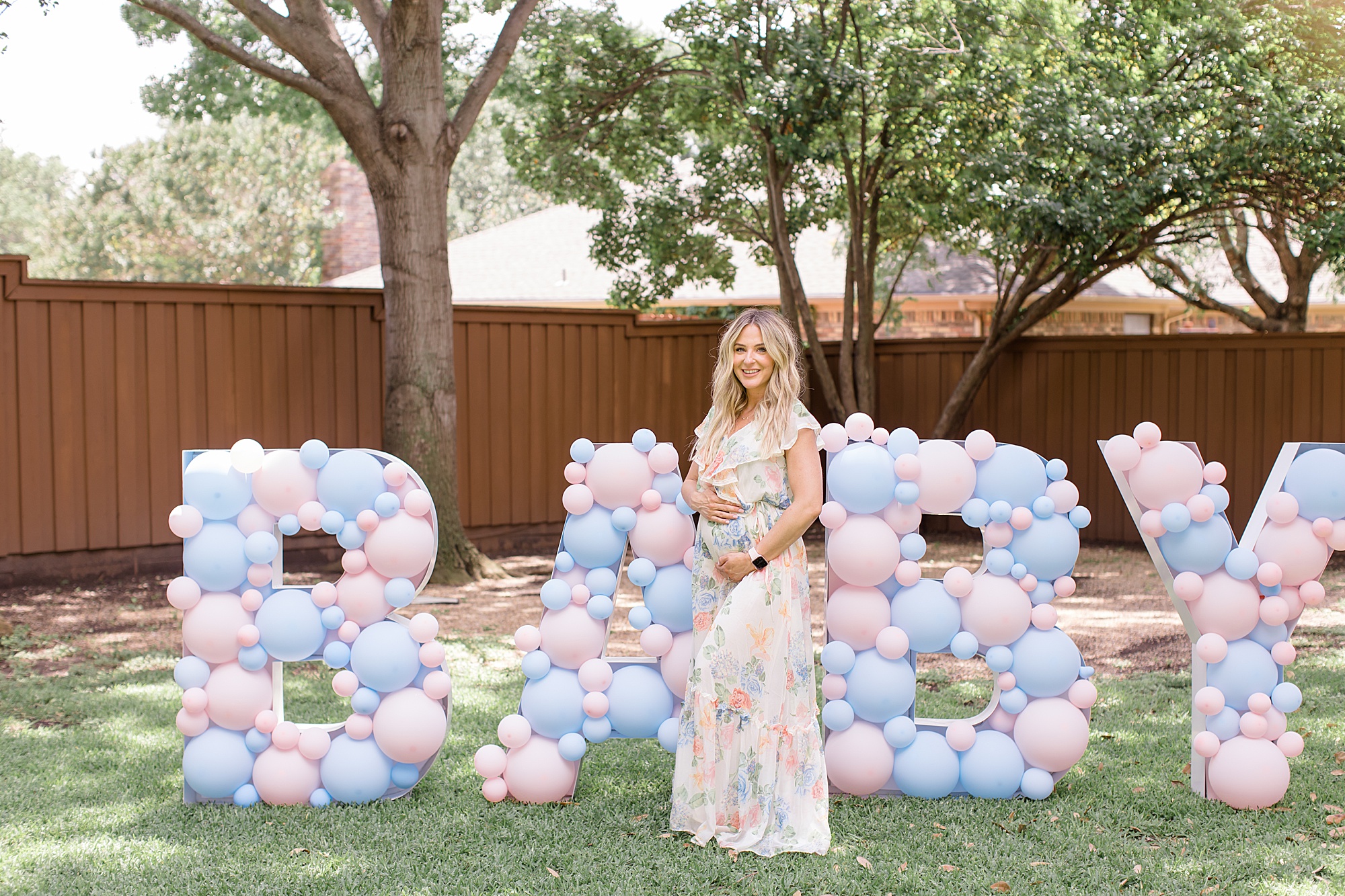 mom poses by BABY sign in backyard