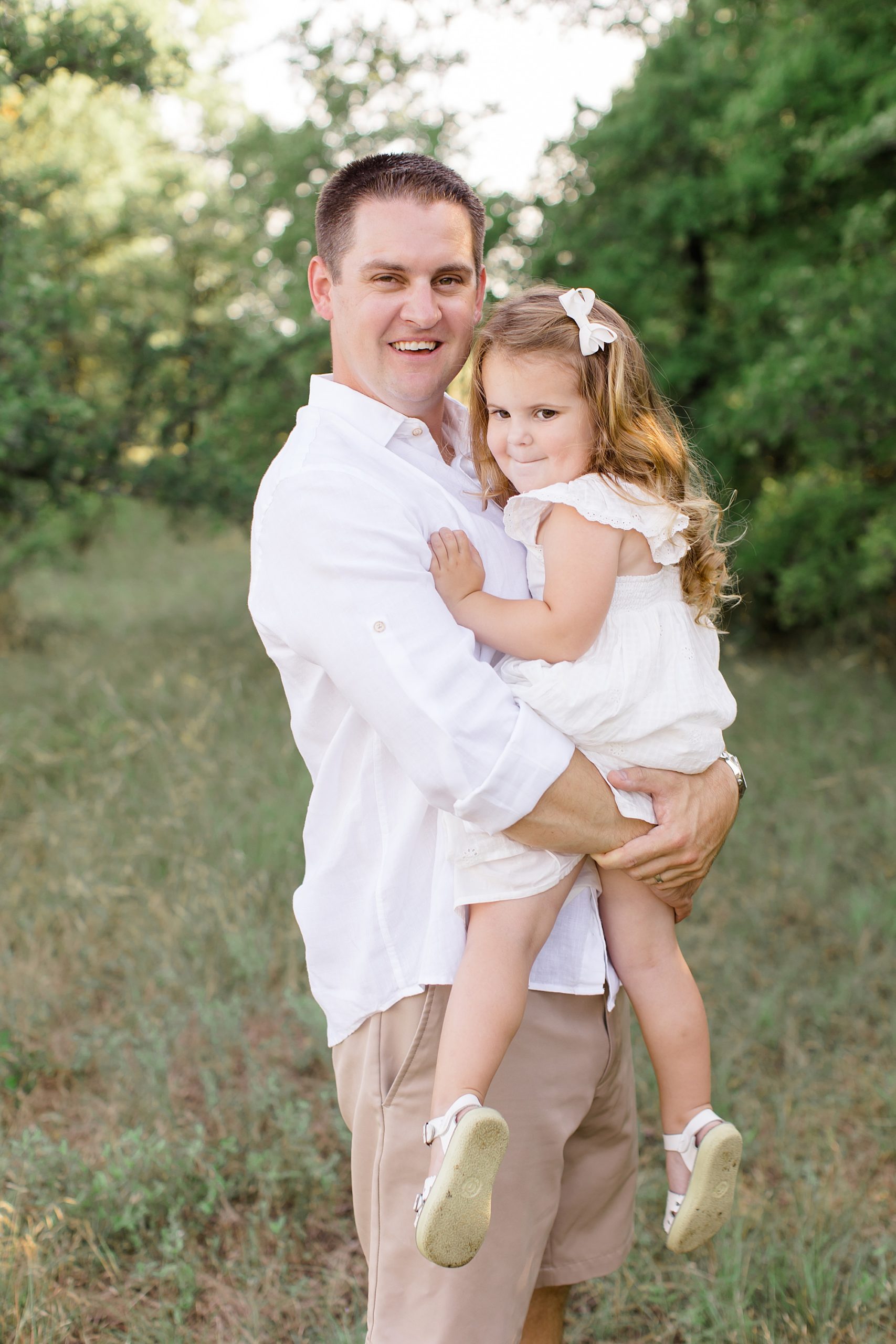 dad holds daughter during spring family portraits at Murrell Park