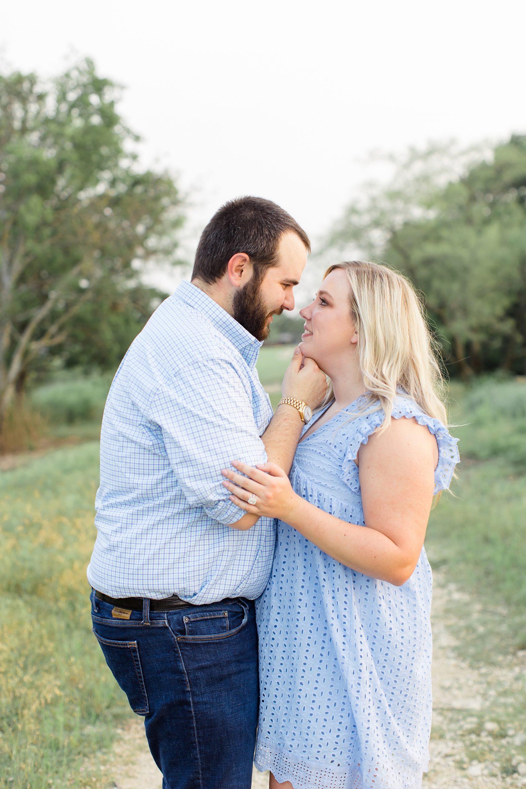 groom holds bride's chin during summer engagement session at Kimball Art Museum