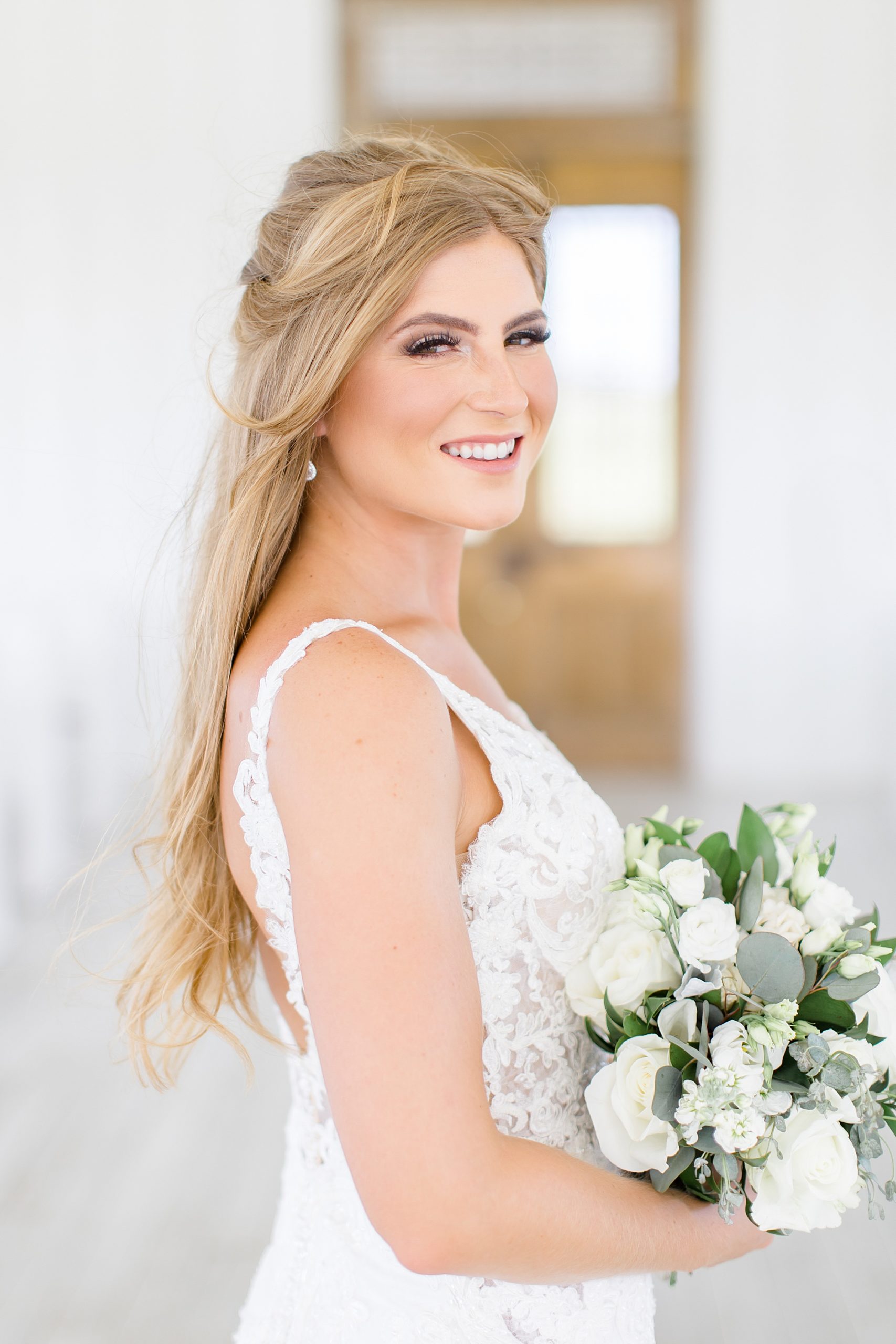 bride looks over shoulder holding bouquet of white flowers