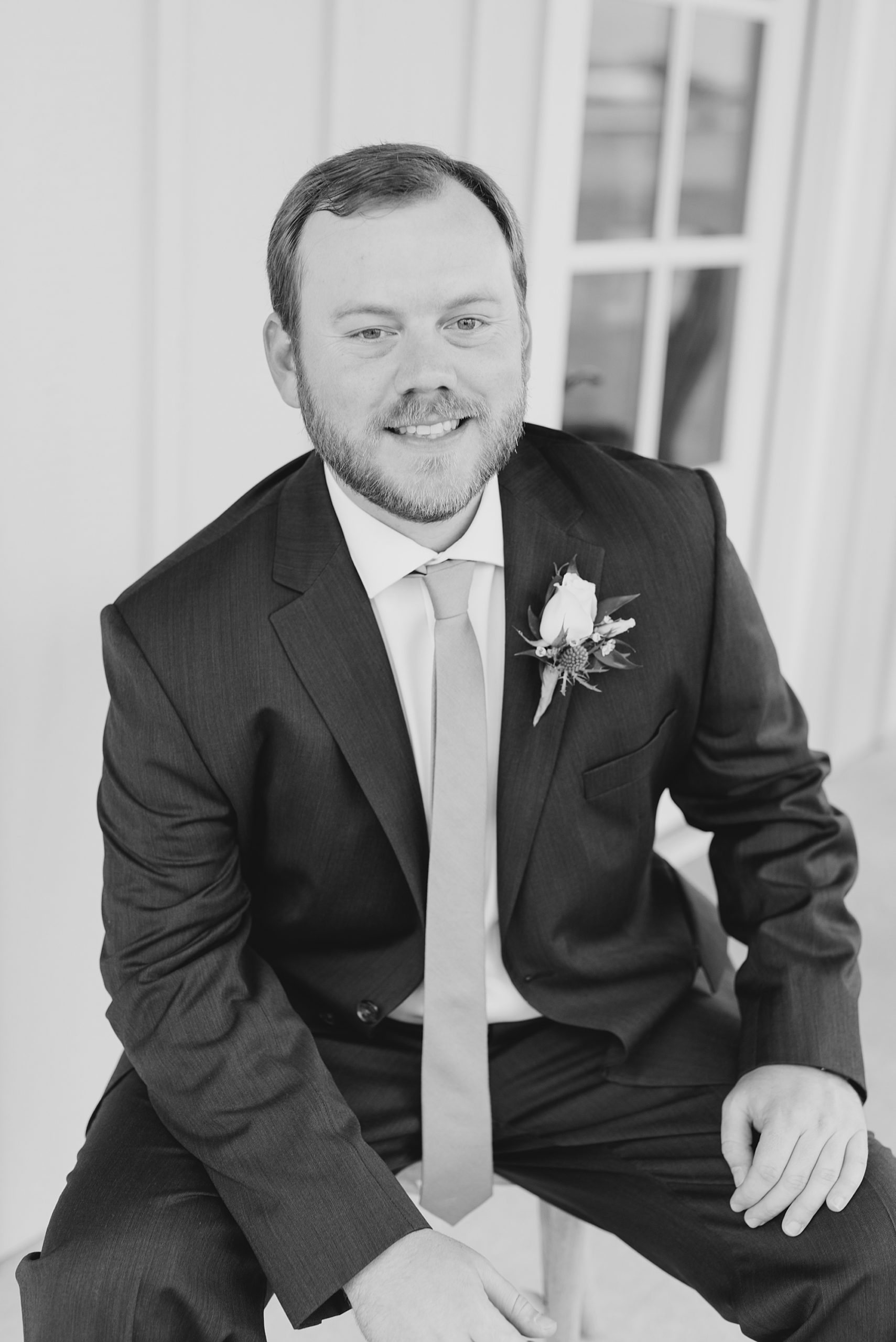 groom in classic suit sits showing off boutonnière