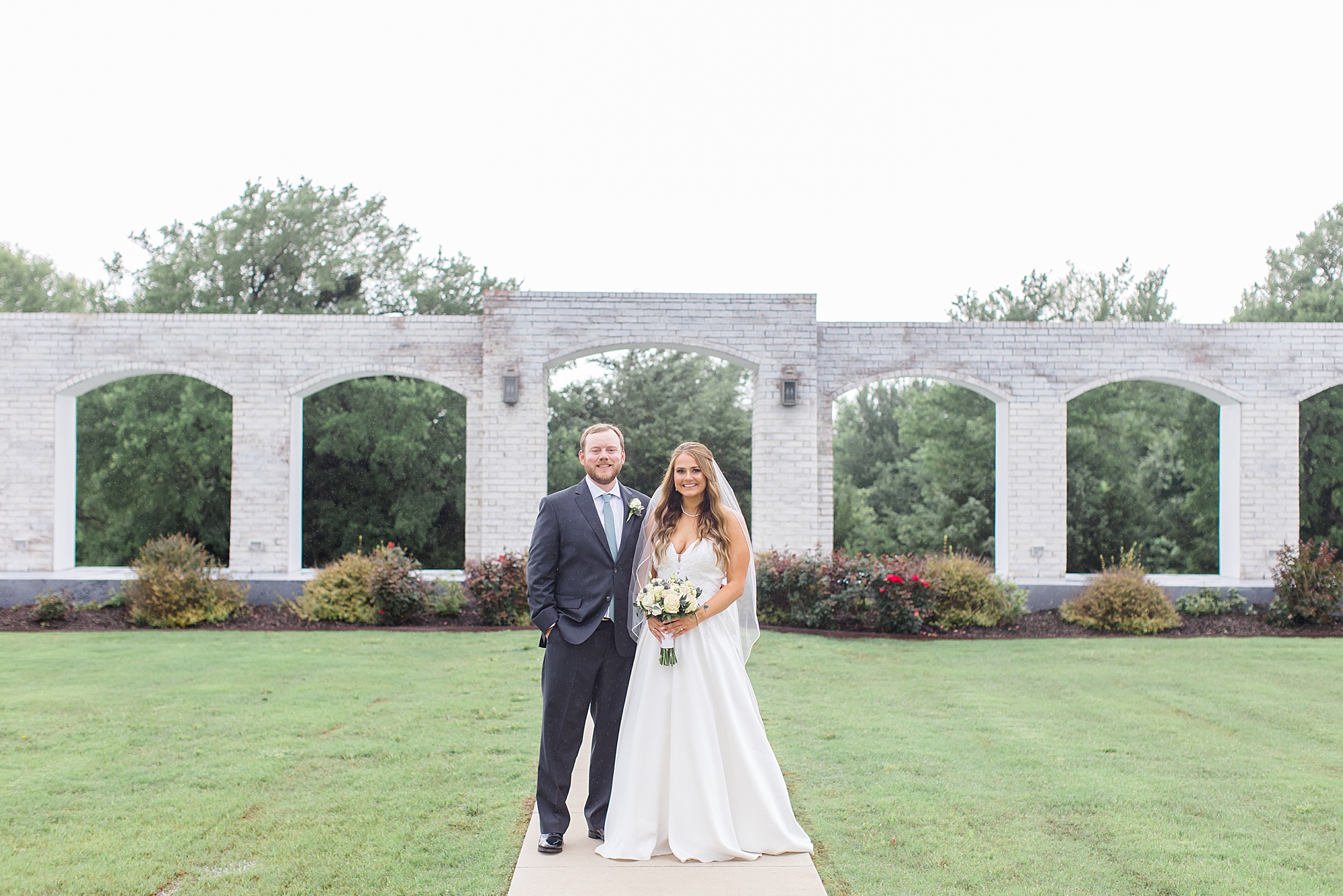 newlyweds pose by stone wall