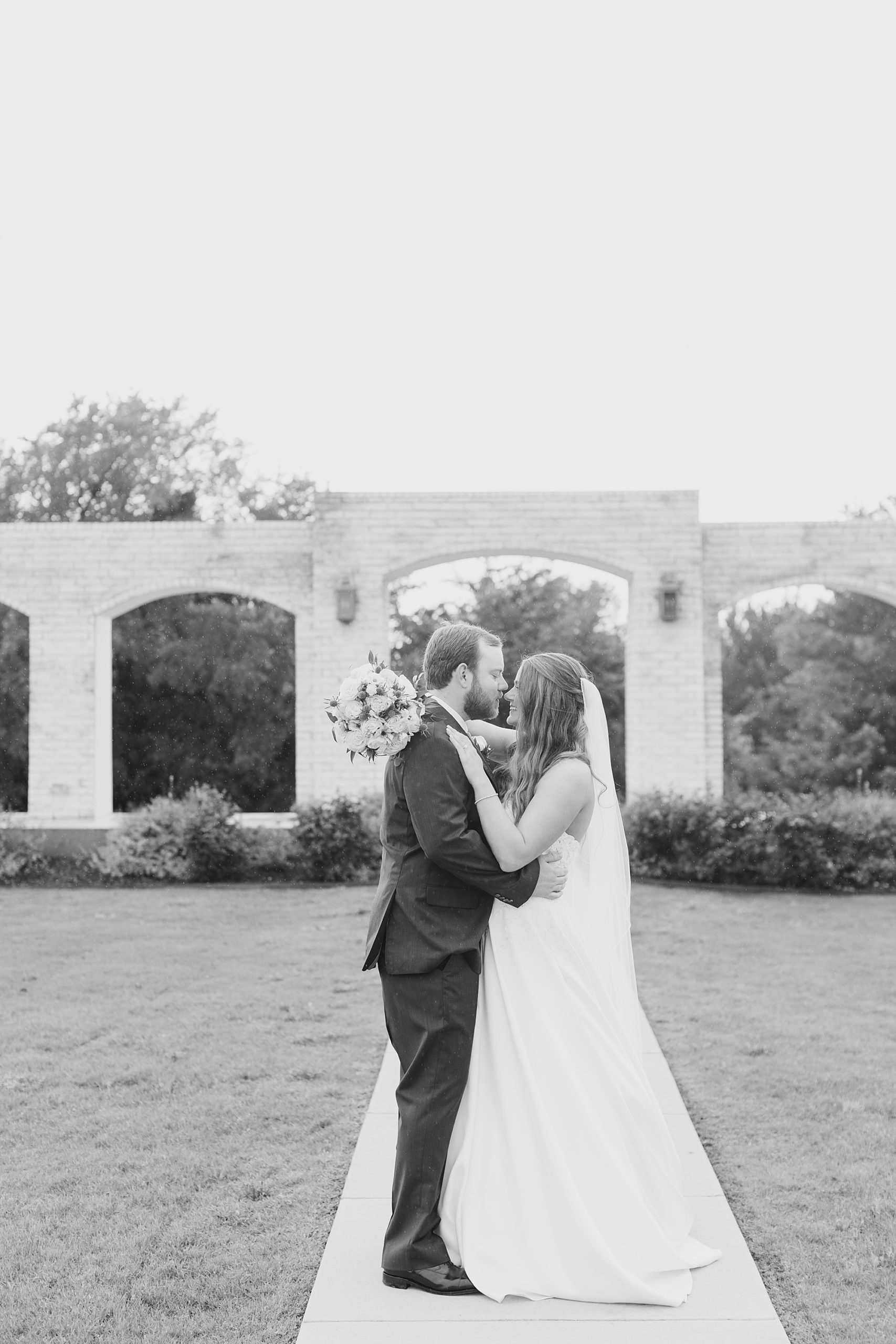 bride and groom kiss by stone wall at The Grand Ivory