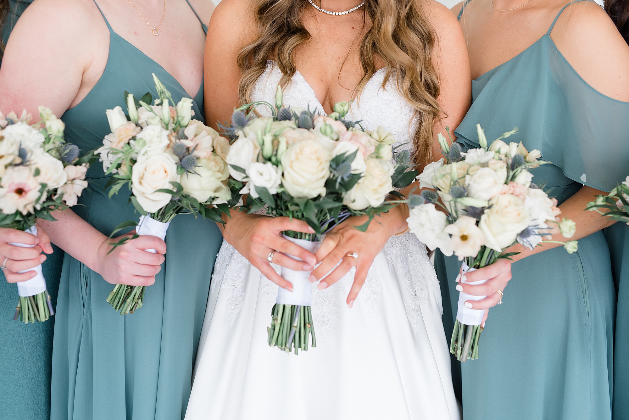 bride and bridesmaids hold ivory bouquets 