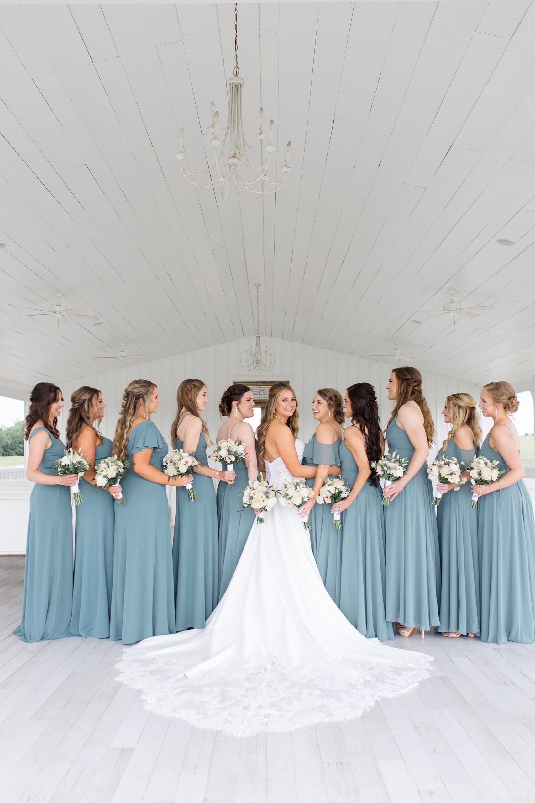 bride and bridesmaids in teal gowns hug at The Grand Ivory