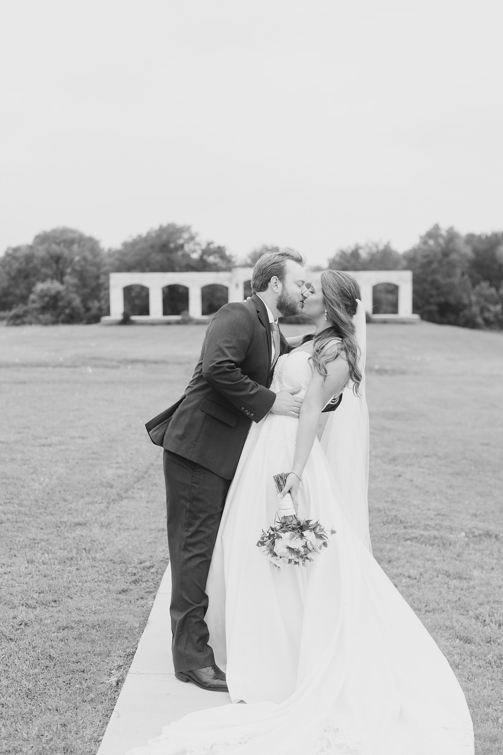 bride and groom kiss by stone wall in Texas