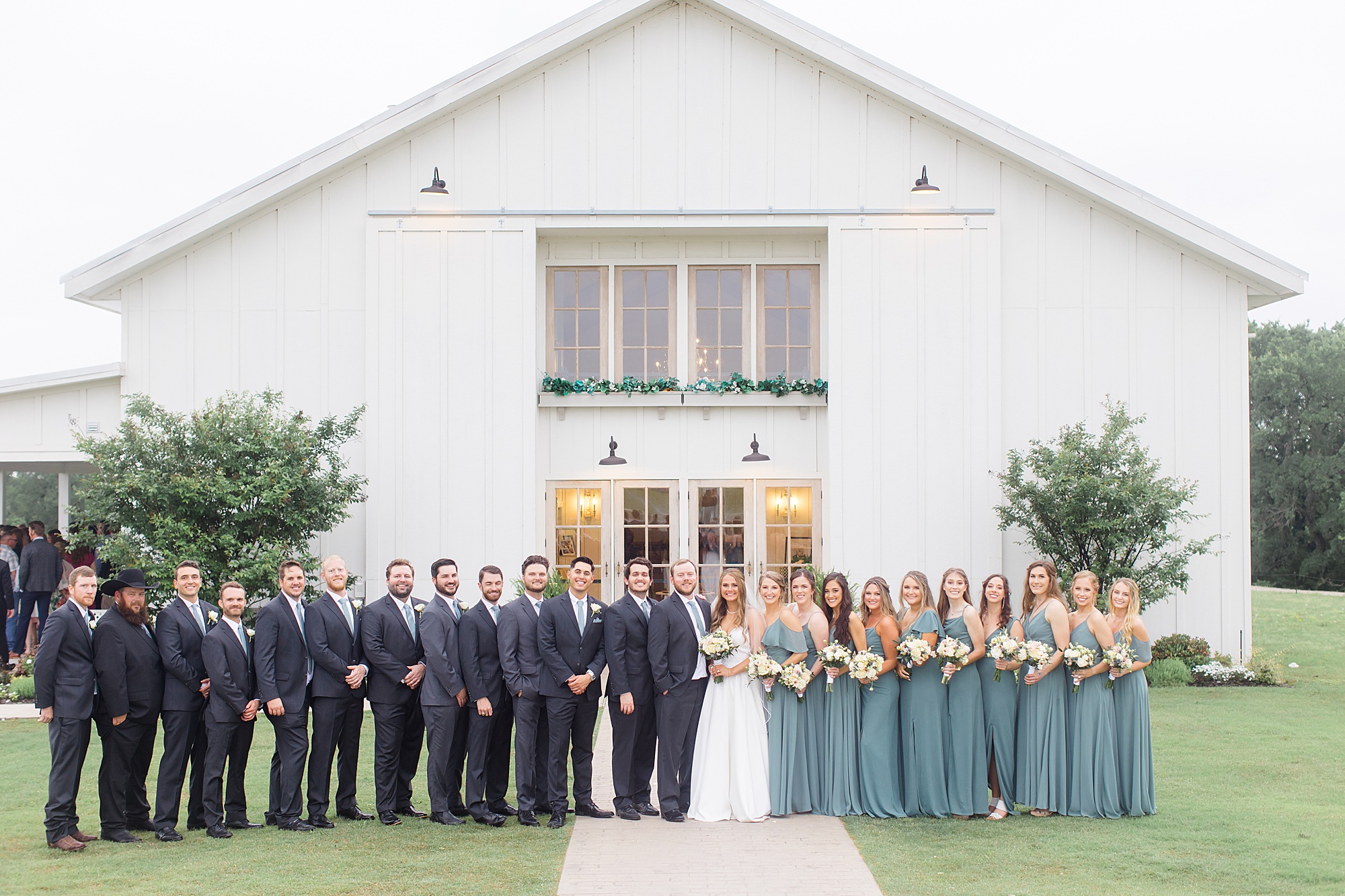bride and groom pose with wedding party in teal and grey