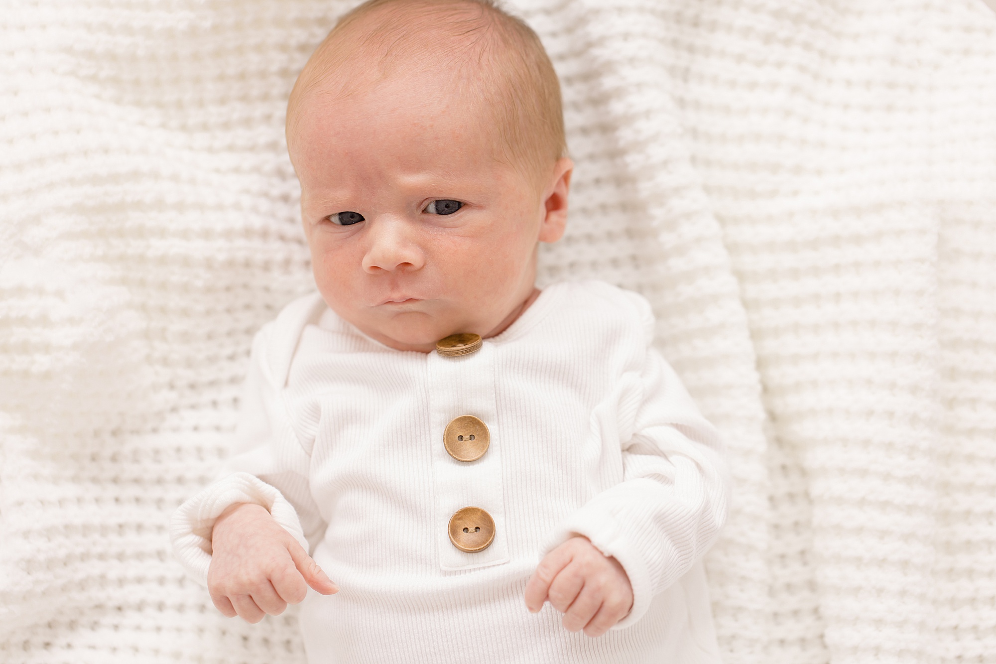 baby makes scowling face during lifestyle newborn session in Texas