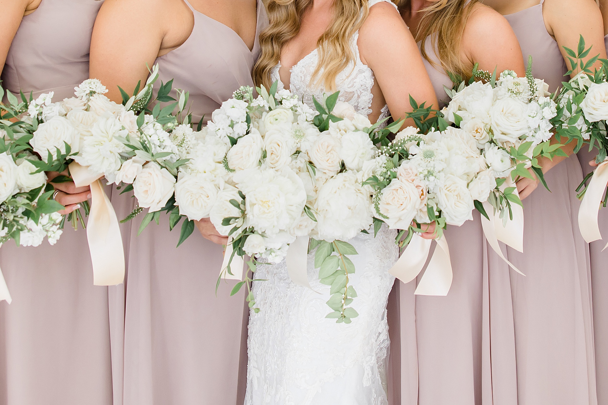 bride and bridesmaids hold ivory bouquets for summer wedding