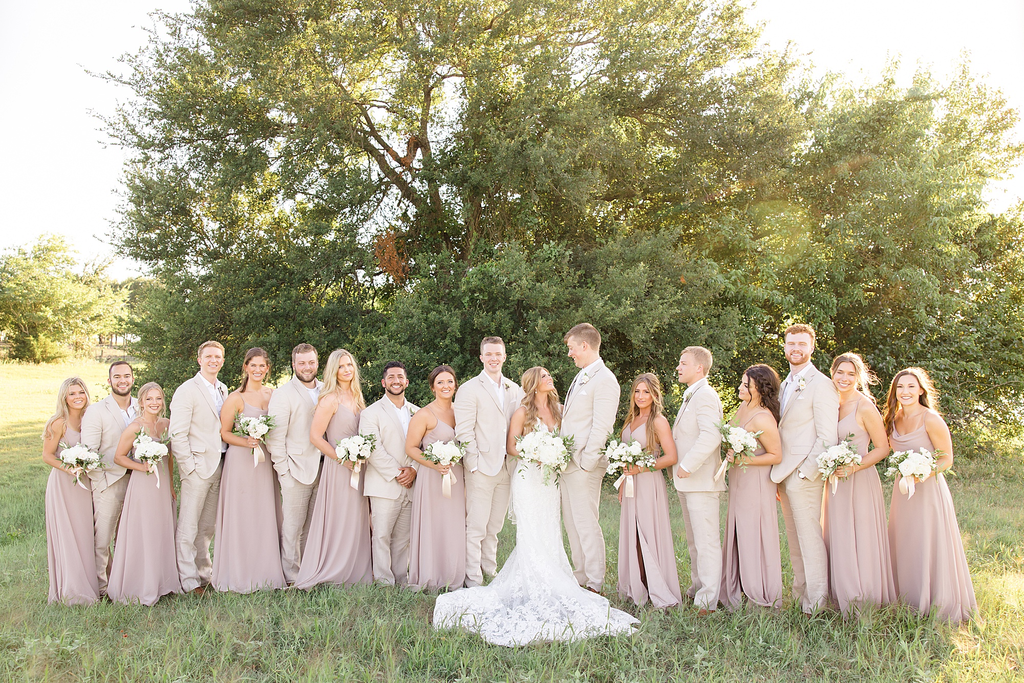wedding party poses with bride and groom outside Dallas venue
