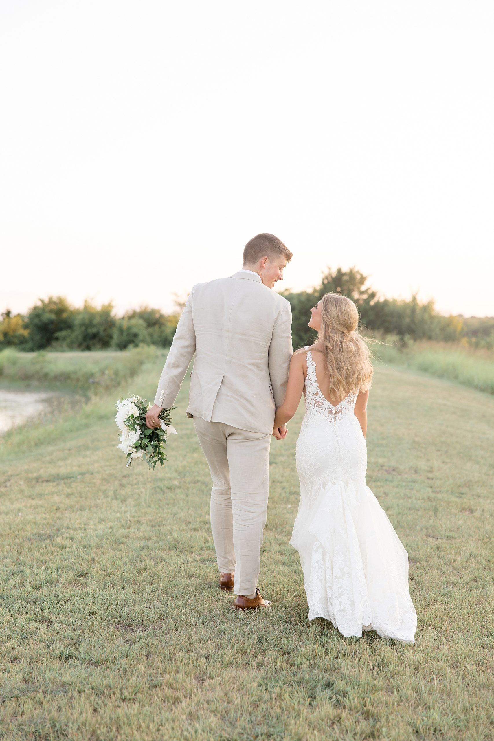 newlyweds walk through field at The Grand Ivory